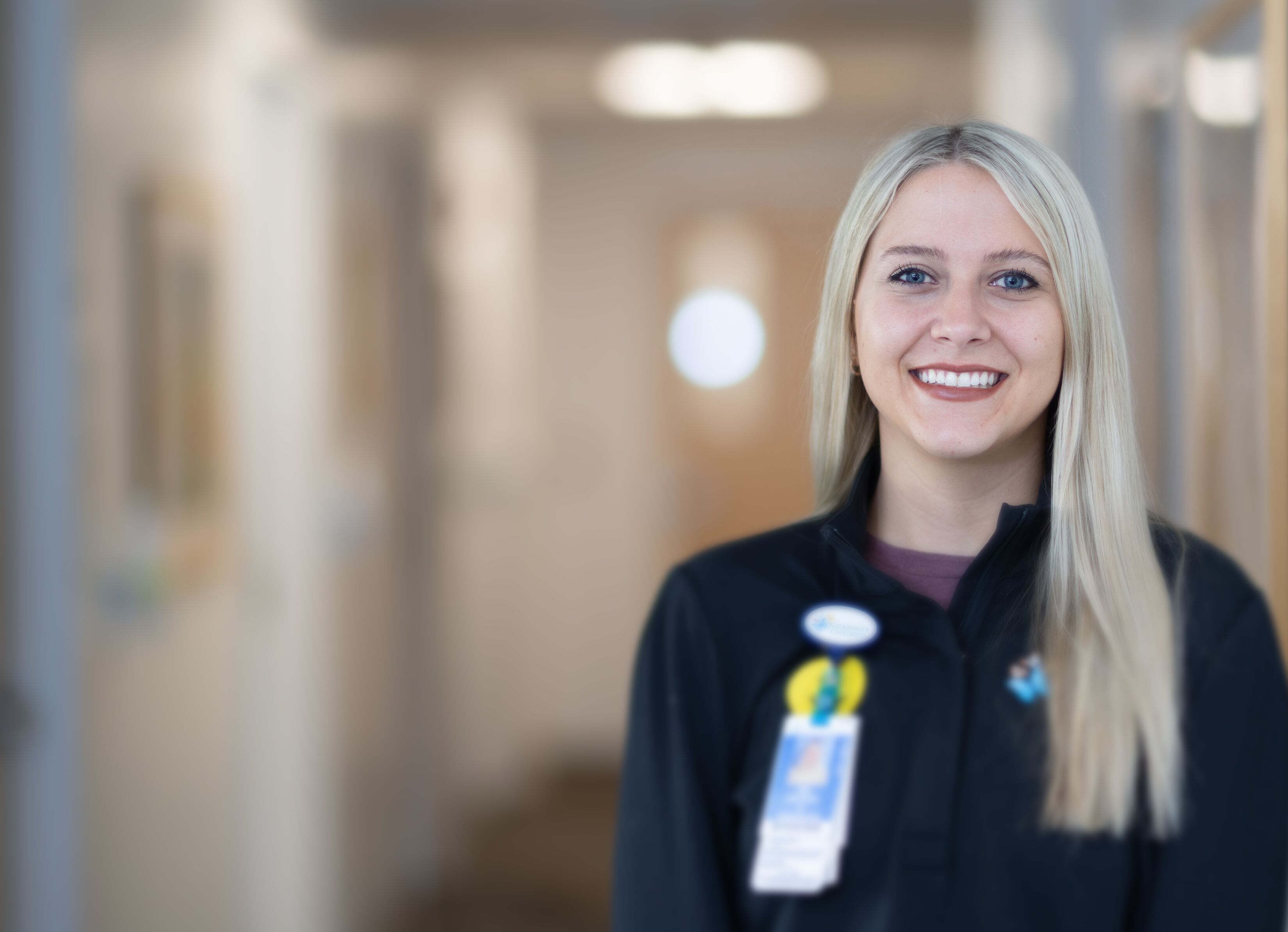 Friendly healthcare professional smiling in a hallway, representing compassionate patient care services.