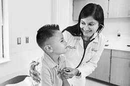 Doctor listening to patient's heart beat in exam room