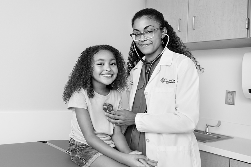 Doctor listening to patient's heartbeat in exam room
