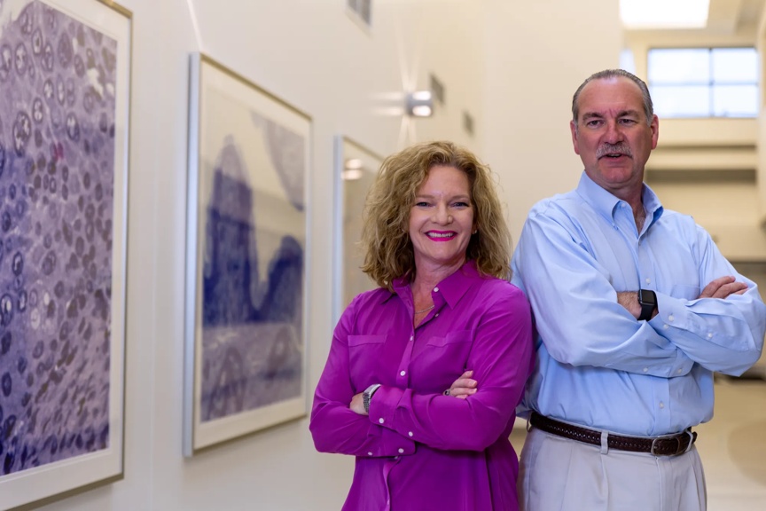 Two researchers standing in a hallway back to back.