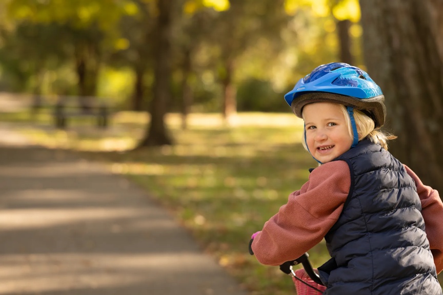 Toddler wearing a helmet while riding a balance bike outdoors