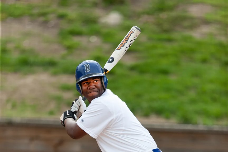 A young player in a baseball uniform prepares to bat, focusing intently with a baseball bat in hand.