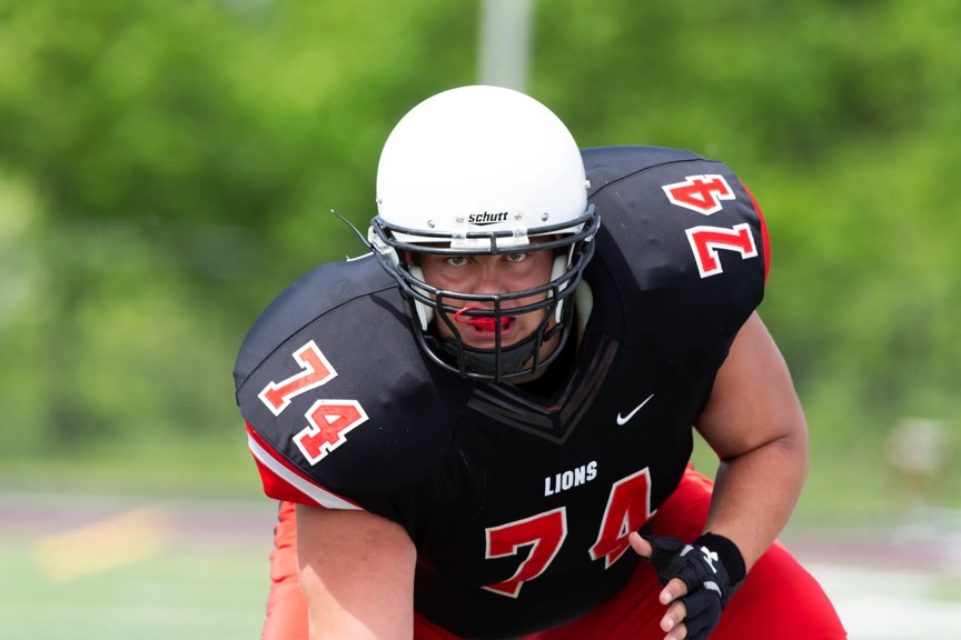 A football player is wearing a black and red uniform with a white helmet