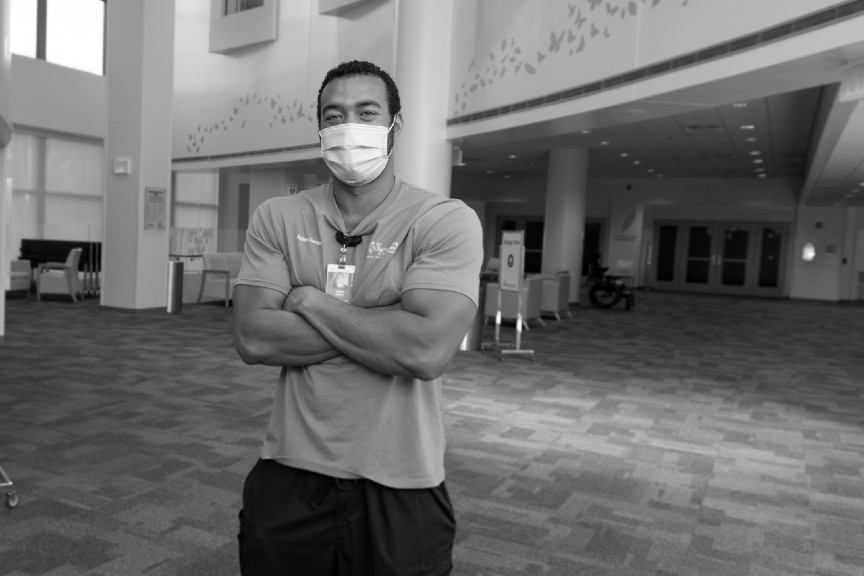 Anthony is shown standing in an open area at Nationwide Children's. His arms are crossed. He is wearing a mask, but you can tell he is smiling.