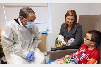 Dr. Mendell is seated, in conversation with the young patient