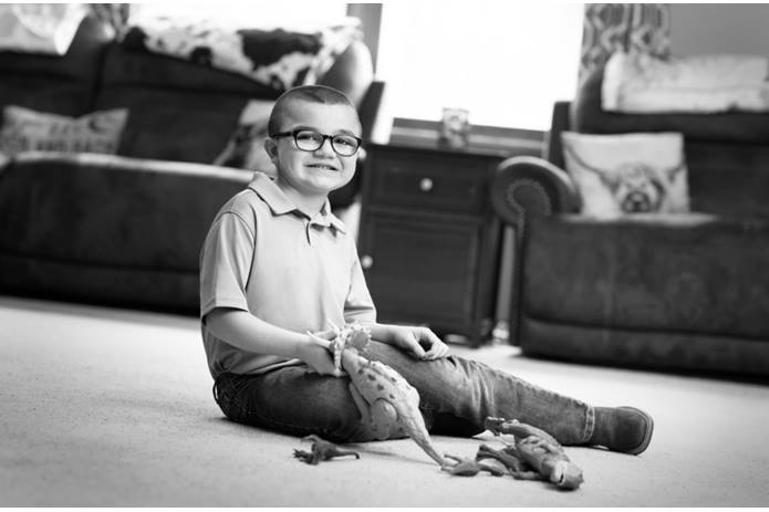 A child with Duchenne muscular dystrophy sitting on the floor holding dinosaur figurines while being treated at Nationwide Children's.