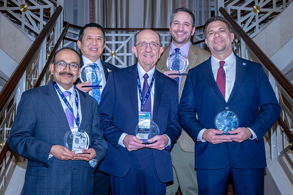 Group of five professionals in suits holding glass awards at an event; Dr. Henry Xiang (second from left) recognized as an inaugural Fellow of the Society for Advancement of Violence and Injury Research (SAVIR) and the American Medical Extended Reality Association (AMXRA).