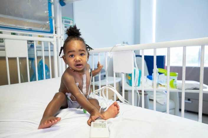 Toddler being treated at hospital sitting in a crib