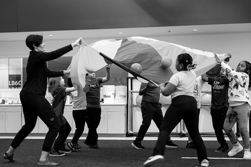 A group of kids are in a circle, playing, holding up a large piece of fabric