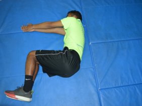 Athletic trainer lies on side on the ground, arms straight and pressed together