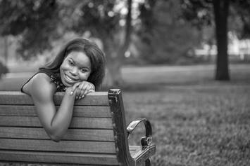 Young Woman Leaning Against Bench Smiling