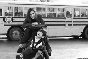 image of a teen girl standing and a boy sitting in a wheelchair next to a school bus